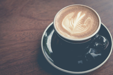 Top view of a cup of coffee with heart pattern in a black cup