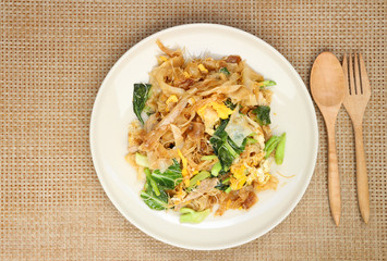 Fried noodle with pork and broccoli in black bowl place on wooden table with copy space for your text and design. Concept be used for menu presentation at cafe and restaurant. top view