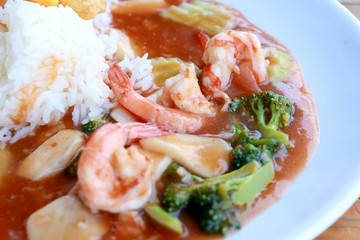 stir fried shrimp and Broccoli in thai red curry paste sauce with rice, Curry fried shrimps and cooked rice in white dish closeup on wooden table. Thai style food.