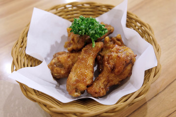 Fried chicken wings in white plate on wooden table..