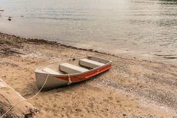 small wooden boat with red siding tied on the shore on a cloudy day