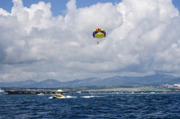 Boat with a floating parachute on a rope leaving into the sea.