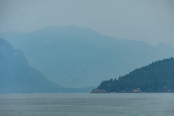 layered mountains behind Island near coast under the heavy smoke in the morning 