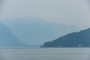 layered mountains behind Island near coast under the heavy smoke in the morning 
