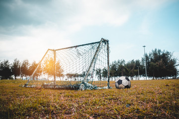 Football gate or soccer goal in neglected on field with football.