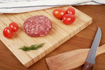 Raw cutlet of minced meat on a wooden cutting board.