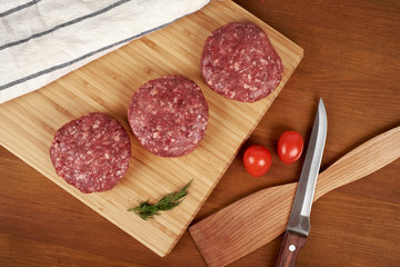 Raw cutlet of minced meat on a wooden cutting board.