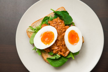 Healthy natural high protein snack whole grain toast with soft boiled egg, tuna and spinach