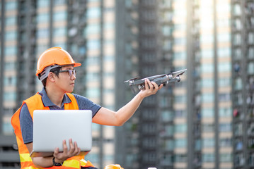 Asian engineer man working with drone and laptop computer at construction site. Using unmanned...