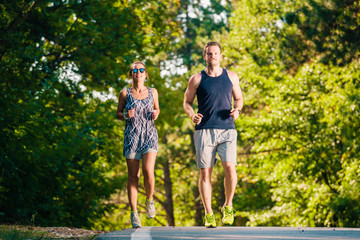 Athletic couple running on sunset in the city park. Working out in the city urban area.