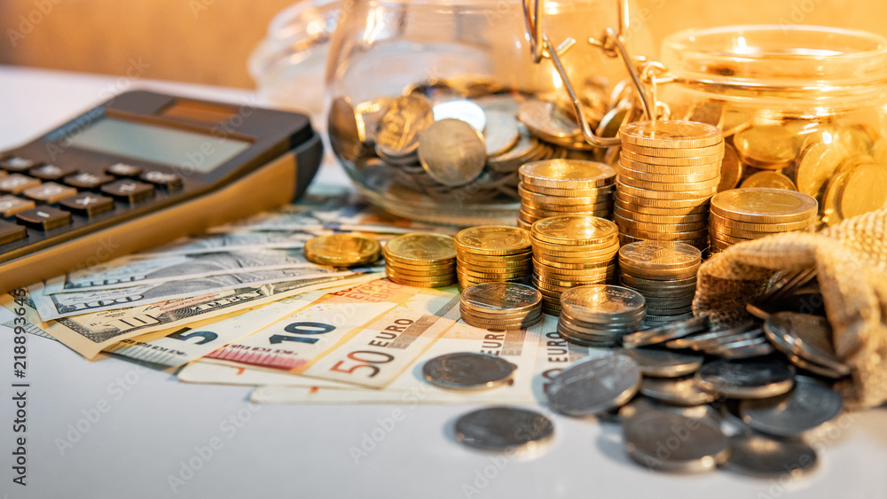 Une calculatrice, des pièces et des billets sur une table