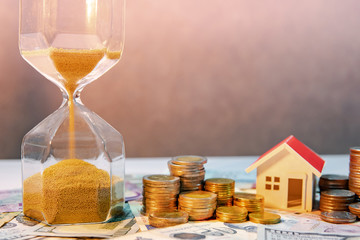 Saving money for retirement concept. Real estate or property investment. Home mortgage loan rate. Gold coin stack, house model and hourglasses on international banknotes.