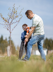 Naklejka na ściany i meble son and father plant a tree and talk