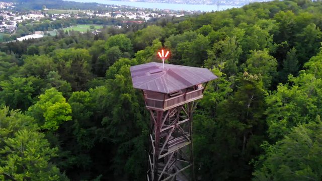 4K Aerial drone shot of a tower in the green forest of the city of Z&uuml;rich. The drone is orbiting the tower with two people on it. There is a view of the beautiful forest and nature of Switzerland.