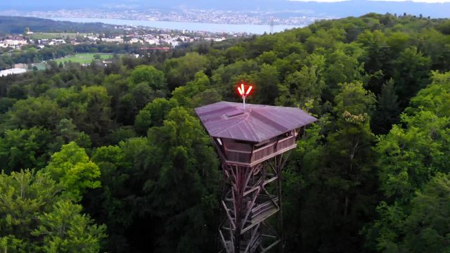 4K Aerial drone shot of a tower in the green forest of the city of Z&uuml;rich. The drone is orbiting the tower with two people on it. There is a view of the beautiful forest and nature of Switzerland.