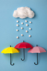Three umbrellas under the cloud on sky blue background