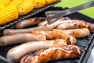 Freshly cooked sausages on a grill with corn close-up. Background of sausages made with charcoal