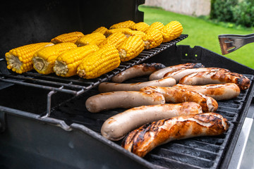Freshly cooked sausages on a grill with corn close-up. Background of sausages made with charcoal