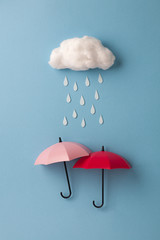 two umbrellas under the cloud on sky blue background