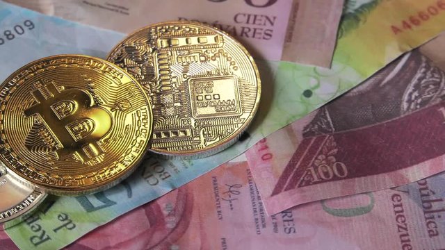 Physical metal Bitcoin currency over bolivar bills. Virtual internet money with Venezuelan banknotes. Digital coin cyberspace, cryptocurrency. BTC golden coin as symbol of electronic virtual money. 4K