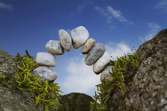 balanced stone arch of pebbles as zen symbol for a bridge or a gate, blue sky