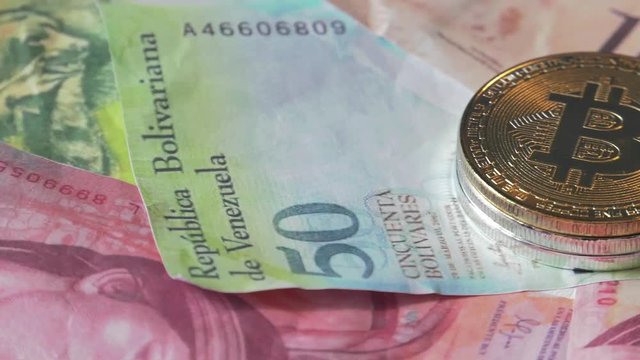 Physical metal Bitcoin currency over bolivar bills. Virtual internet money with Venezuelan banknotes. Digital coin cyberspace, cryptocurrency. BTC golden coin as symbol of electronic virtual money. 4K