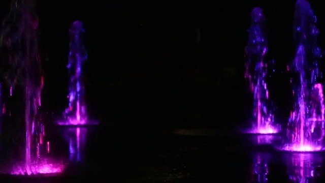 Colored water night fountain dancing with lights multicolored blur footage background, close up, shallow depth of the field, 59,94 fps