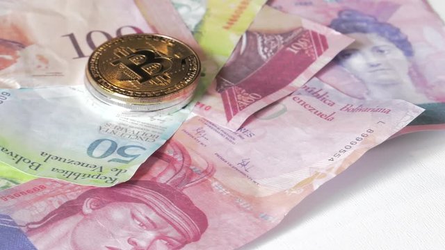 Physical metal Bitcoin currency over bolivar bills. Virtual internet money with Venezuelan banknotes. Digital coin cyberspace, cryptocurrency. BTC golden coin as symbol of electronic virtual money. 4K