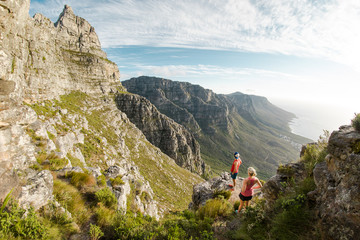 Two trail runners enjoying the view of Table Mountain and the ocean in Cape Town South Africa - obrazy, fototapety, plakaty
