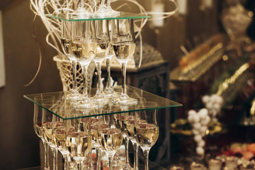 Elegant champagne glasses catering, tiered alcohol drinks on glass table, business dinner party reception in luxury restaurant close-up, catering concept