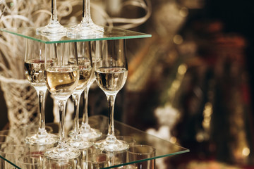 Elegant champagne glasses catering, tiered alcohol drinks on glass table, business dinner party reception in luxury restaurant close-up, catering concept