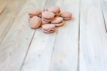 Tasty pink macaroons on a wooden table. It can be used as a background