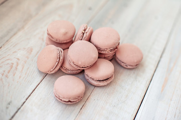 Tasty pink macaroons on a wooden table. It can be used as a background