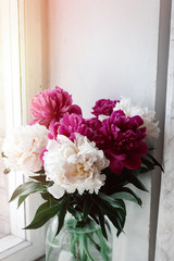 beautiful bunch of peonies in vase on wooden white window sill background, rustic wallpaper concept, space for text
