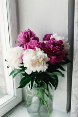 beautiful bunch of peonies in vase on wooden white window sill background, rustic wallpaper concept, space for text