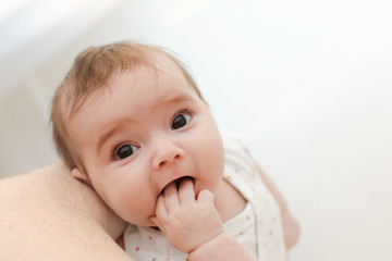 From above shot of cute baby sucking fingers and looking at camera