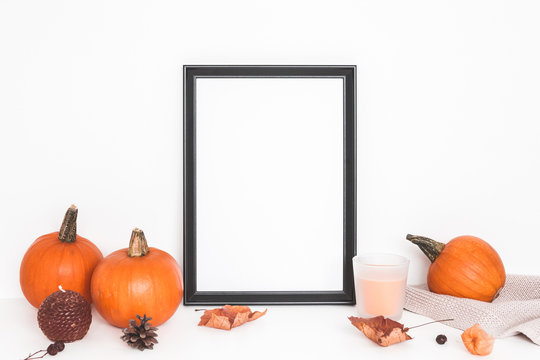 Autumn composition. Photo frame, pumpkins, candles, dried leaves on white background. Autumn, fall, halloween concept. Front view, copy space