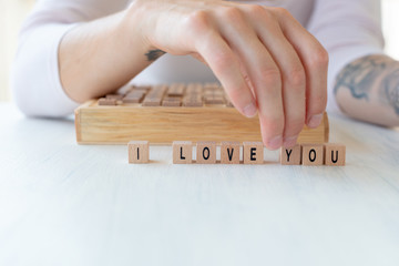 Girl writing I love you with wooden cubes-Valentine card motive