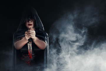 Witch woman holding a bloody knife with smoky background