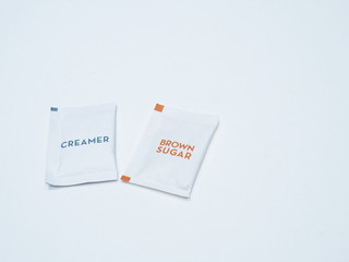 The white paper package of creamer and brown sugar for hot coffee and tea.