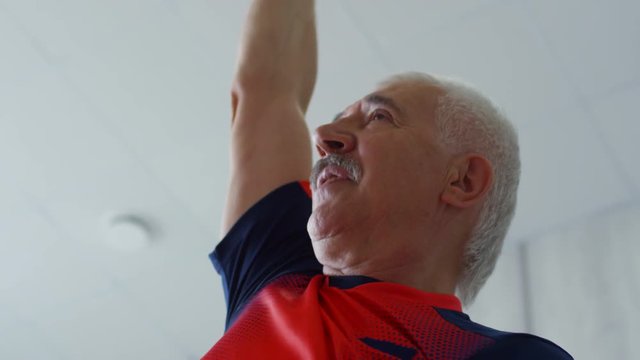 Low Angle Shot Of Cheerful Senior Man With Grey Hair And Moustache Doing Side Bend Stretch, Then Breathing Out And Changing Position