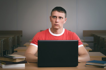 Serious student boy writing a lecture in his laptop computer.