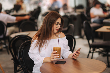Stylish happy young woman wearing white shirt .She holds coffee. portrait of smiling girl in sunglasses