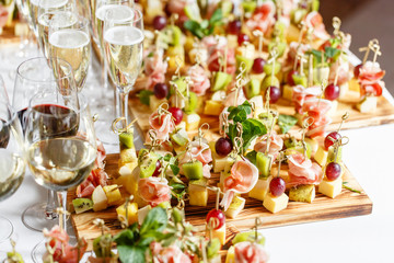solemn happy new year banquet. Lot of glasses champagne or wine on the table in restaurant. buffet table with lots of delicious snacks. canapes, bruschetta, and little desserts on wooden plate board
