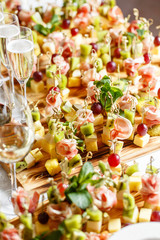 solemn happy new year banquet. Lot of glasses champagne or wine on the table in restaurant. buffet table with lots of delicious snacks. canapes, bruschetta, and little desserts on wooden plate board