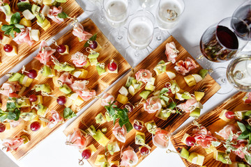 solemn happy new year banquet. Lot of glasses champagne or wine on the table in restaurant. buffet table with lots of delicious snacks. canapes, bruschetta, and little desserts on wooden plate board