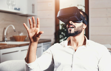 Multicultural bearded man getting experience using VR-headset glasses of virtual reality much...