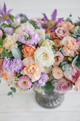 Obraz na płótnie Canvas Gorgeous bouquet of different flowers. floral arrangement in vintage metal vase. table setting. lilac and peach color