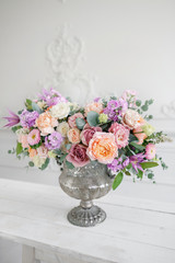 Gorgeous bouquet of different flowers. floral arrangement in vintage metal vase. table setting. lilac and peach color