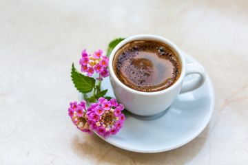 Traditional invigorating Turkish coffee. A white cup of coffee is decorated with flowers. Beautiful feed